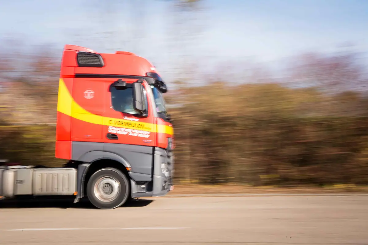 A red and yellow Transport Vermeulen truck on the road